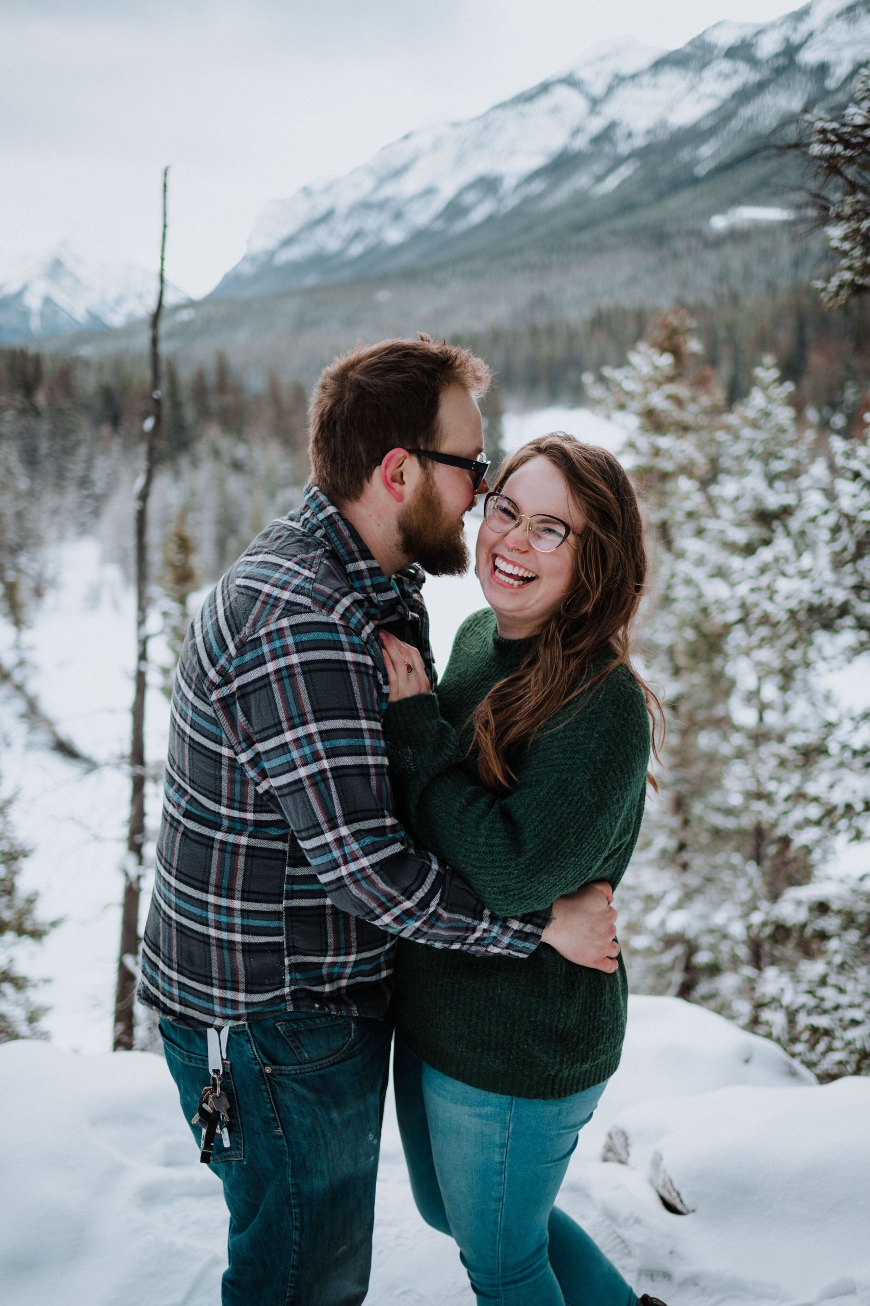 couple laughing in the snowy mountains of alberta canada