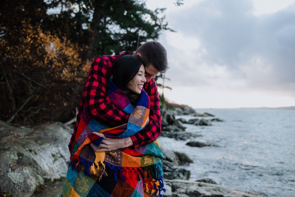 couple snugged in blanket during stormy engagement session